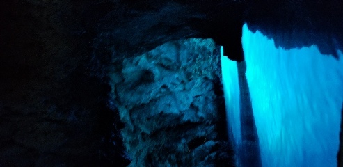 Blue Cave in Croatia. This is a limestone cave with an underwater tunnel to the outside and white sand on the cave floor. When sunlight shines outside the cave, the light reflects off the white sand and into the cave, making it look like the water is glowing a bright blue color.