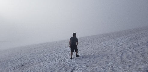 Hiking across a snow field in near whiteout conditions on Mount Rainier in order to get above the clouds